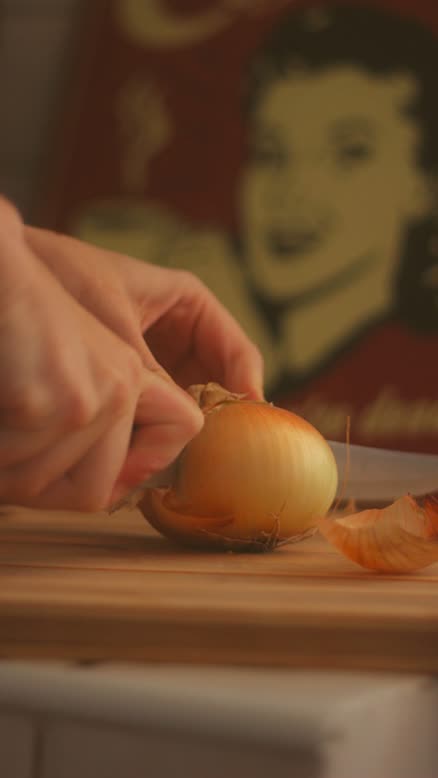 Manos pelando una cebolla sobre una tabla de madera